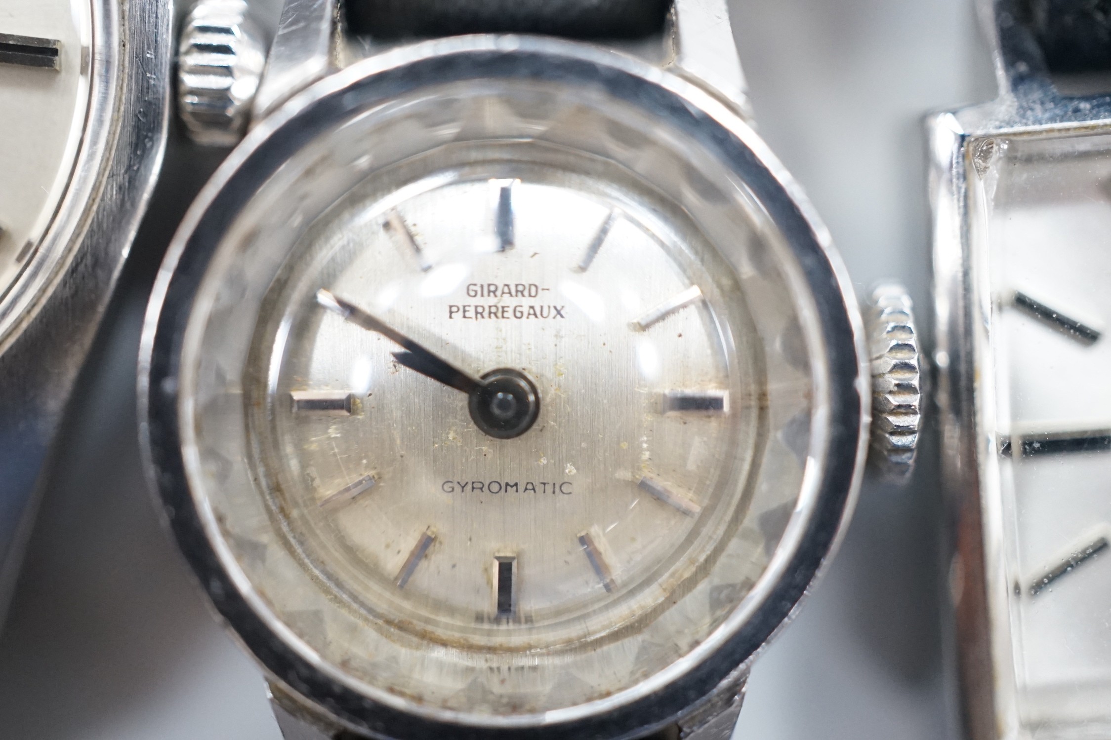 A lady's stainless steel Omega manual wind wrist watch, with baton numerals, together with a lady's stainless steel Zenith square dial manual wind wrist watch and a similar Girard Perregaux manual wind wrist watch.